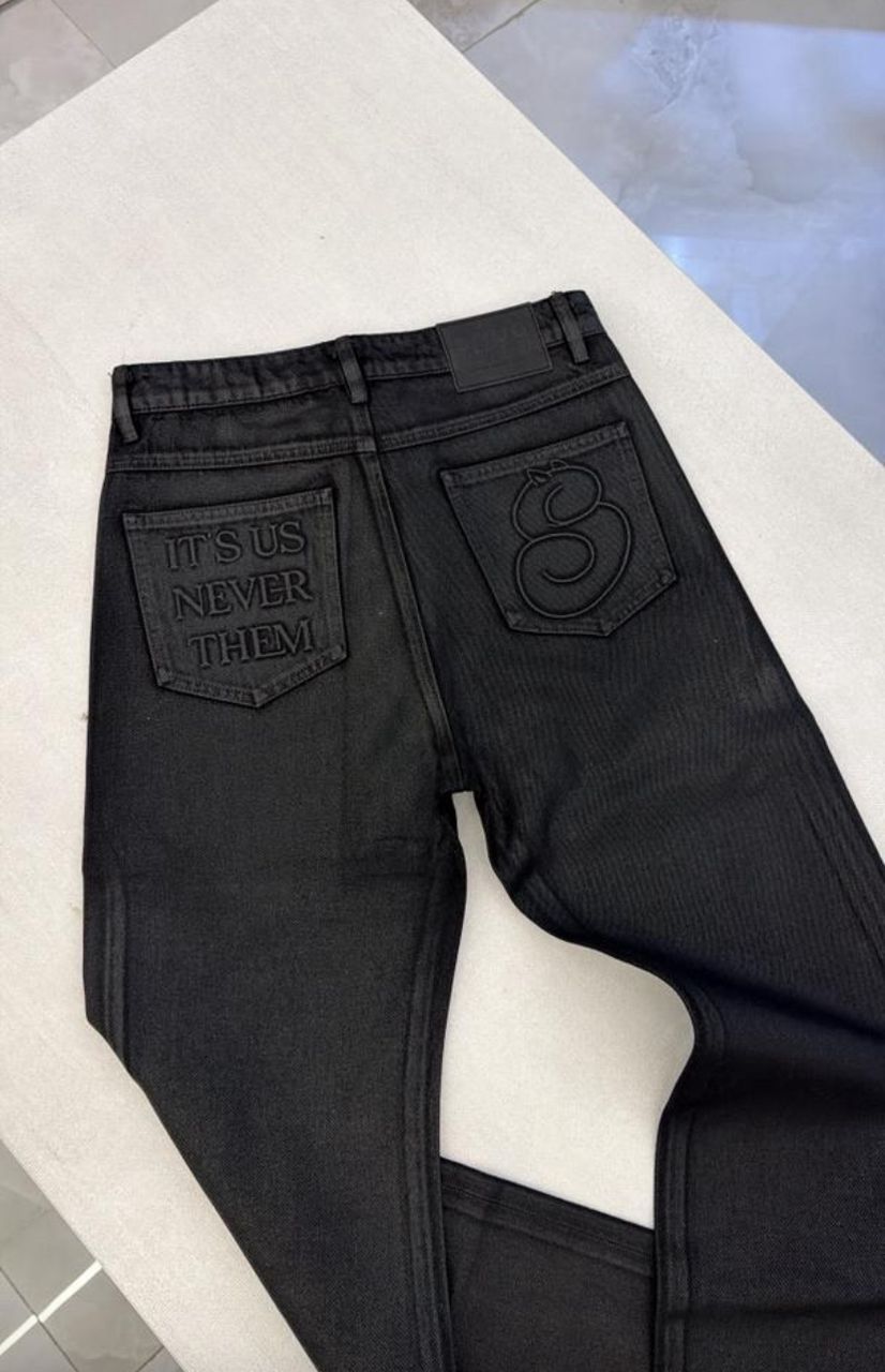 Black jeans with text and logo on a white surface