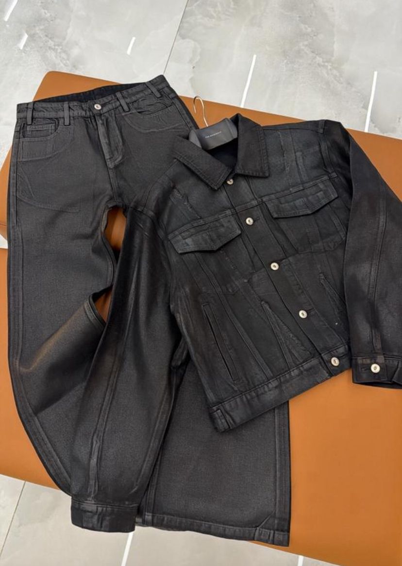 Black denim jacket and pants on a brown surface with a light gray floor background